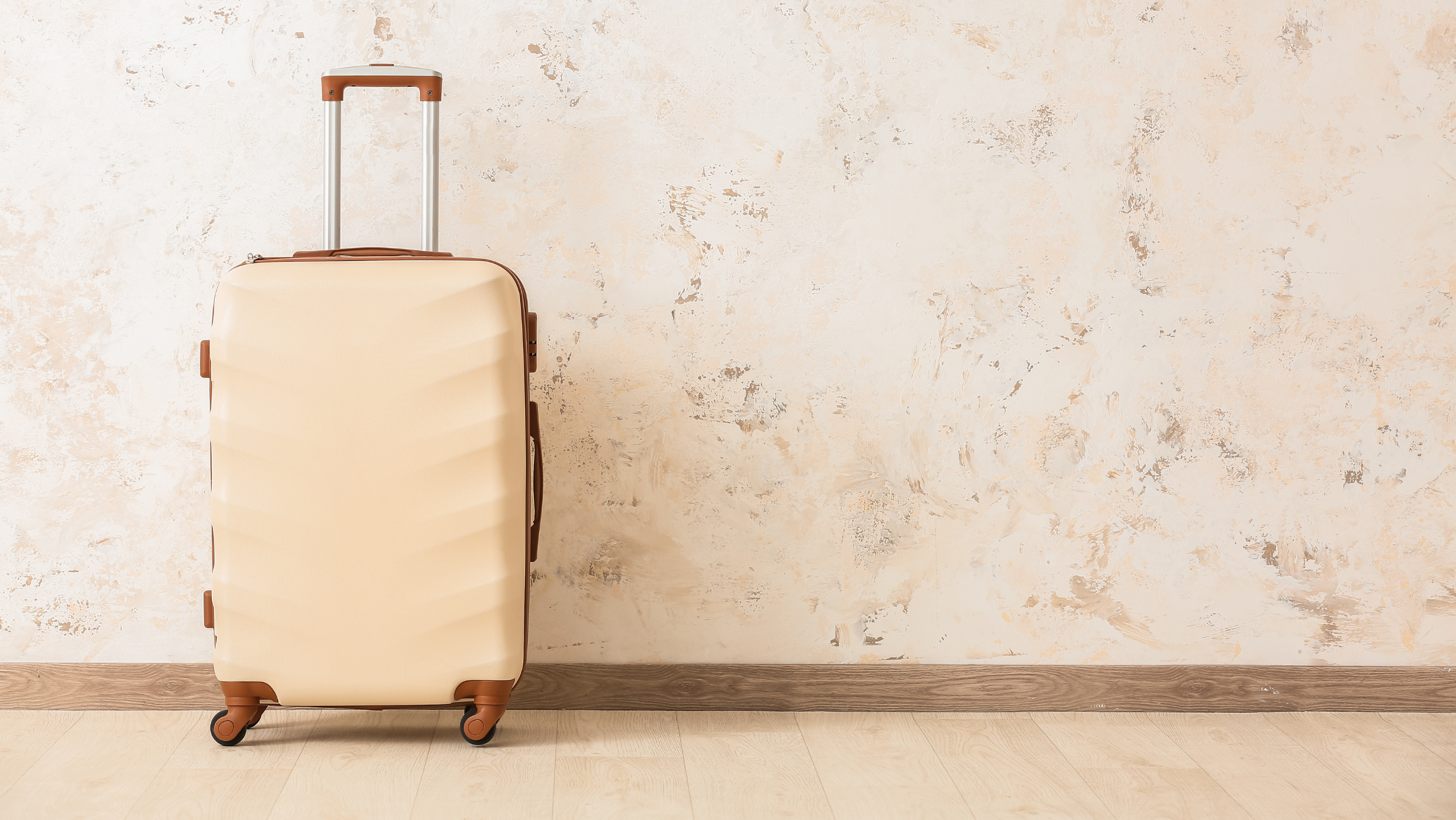 beige suitcase against textured wall